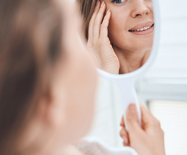 woman looking at a mirror with clear skin